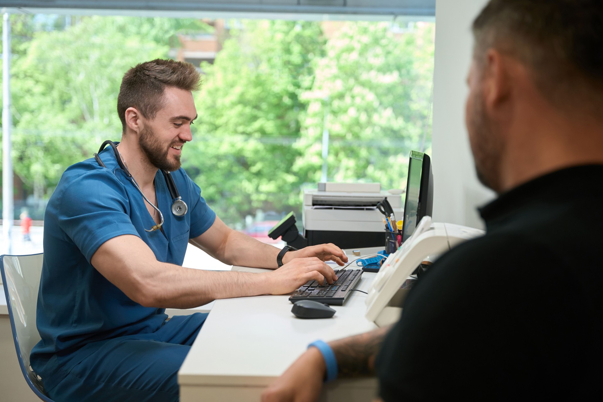Friendly doctor entering patient data into PC